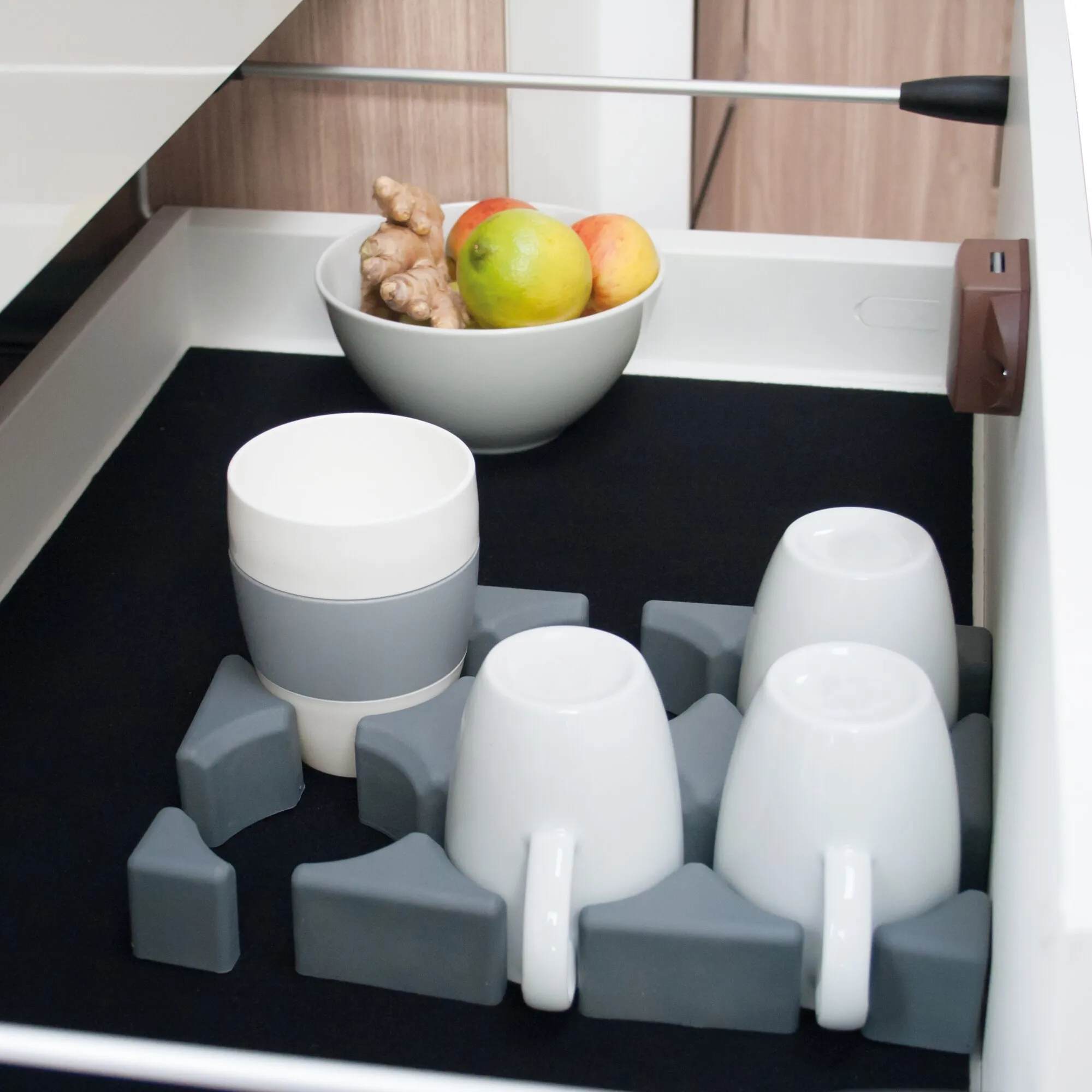 Vario System, Modul I mit weißen und grauen modularen Halteelementen in einem schwarzen Auszug und Obstschale im Hintergrund