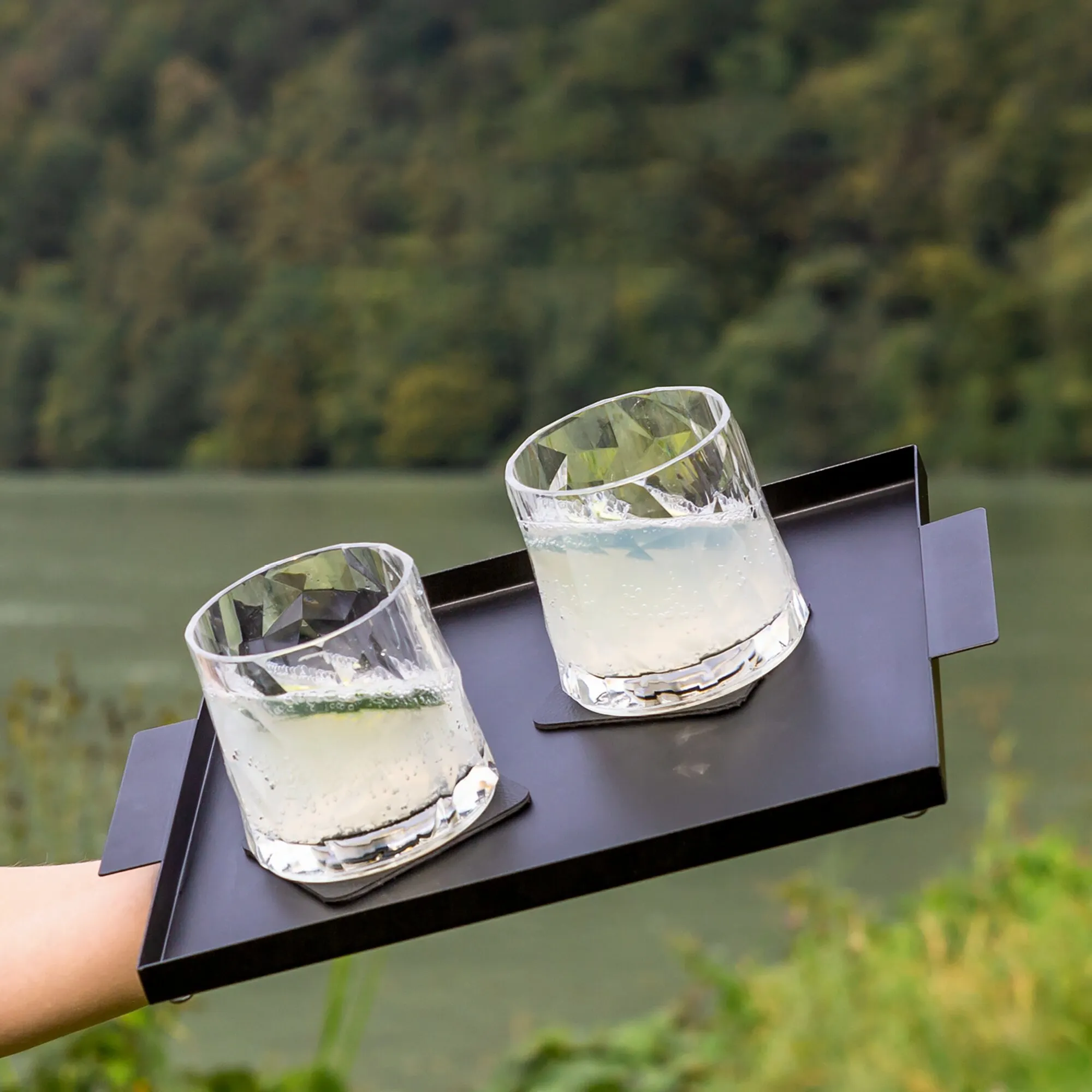 Drei transparente, facettierte Whisky-Kunststoffgläser mit Getränken auf einem schwarzen Tablett im Außenbereich, magnetisch fixiert