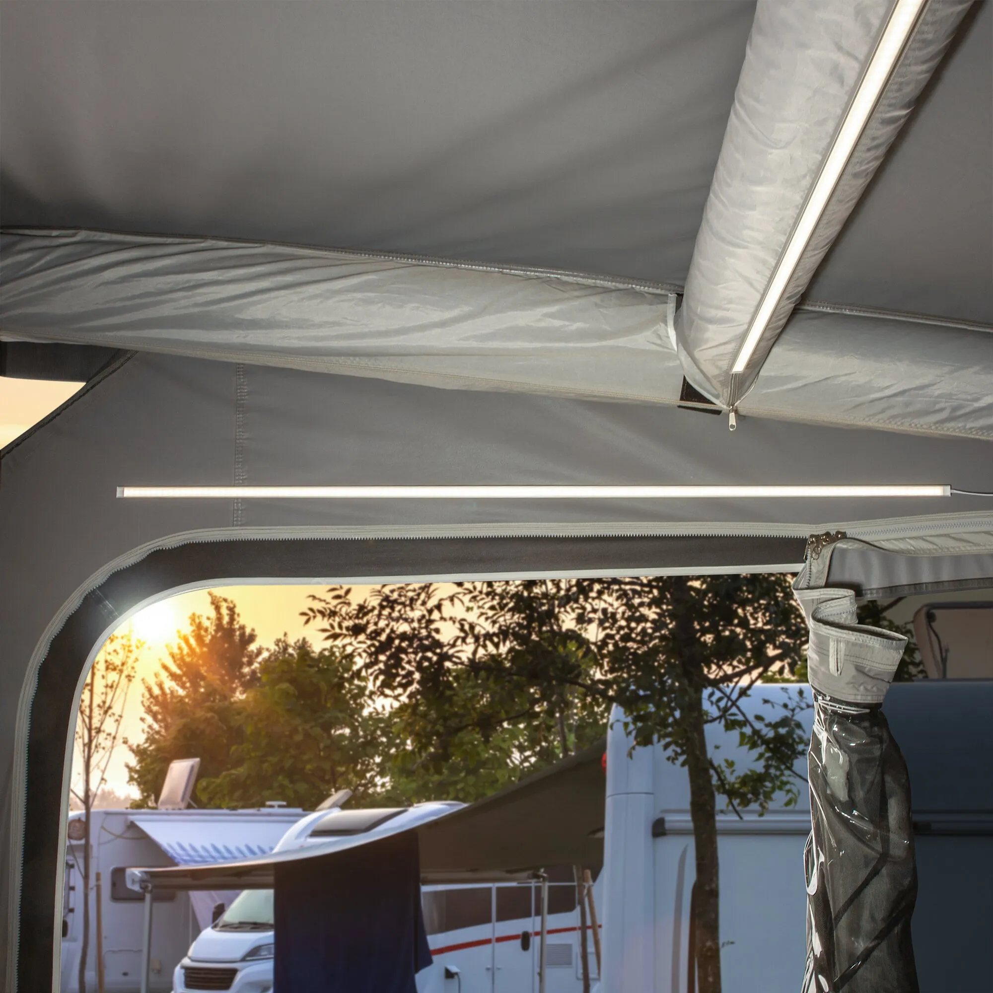 Beleuchtete LED-Lichtleisten im grauen Vorzelt eines Wohnmobils, eine an der Zeltstange und eine quer unter dem Dach befestigt