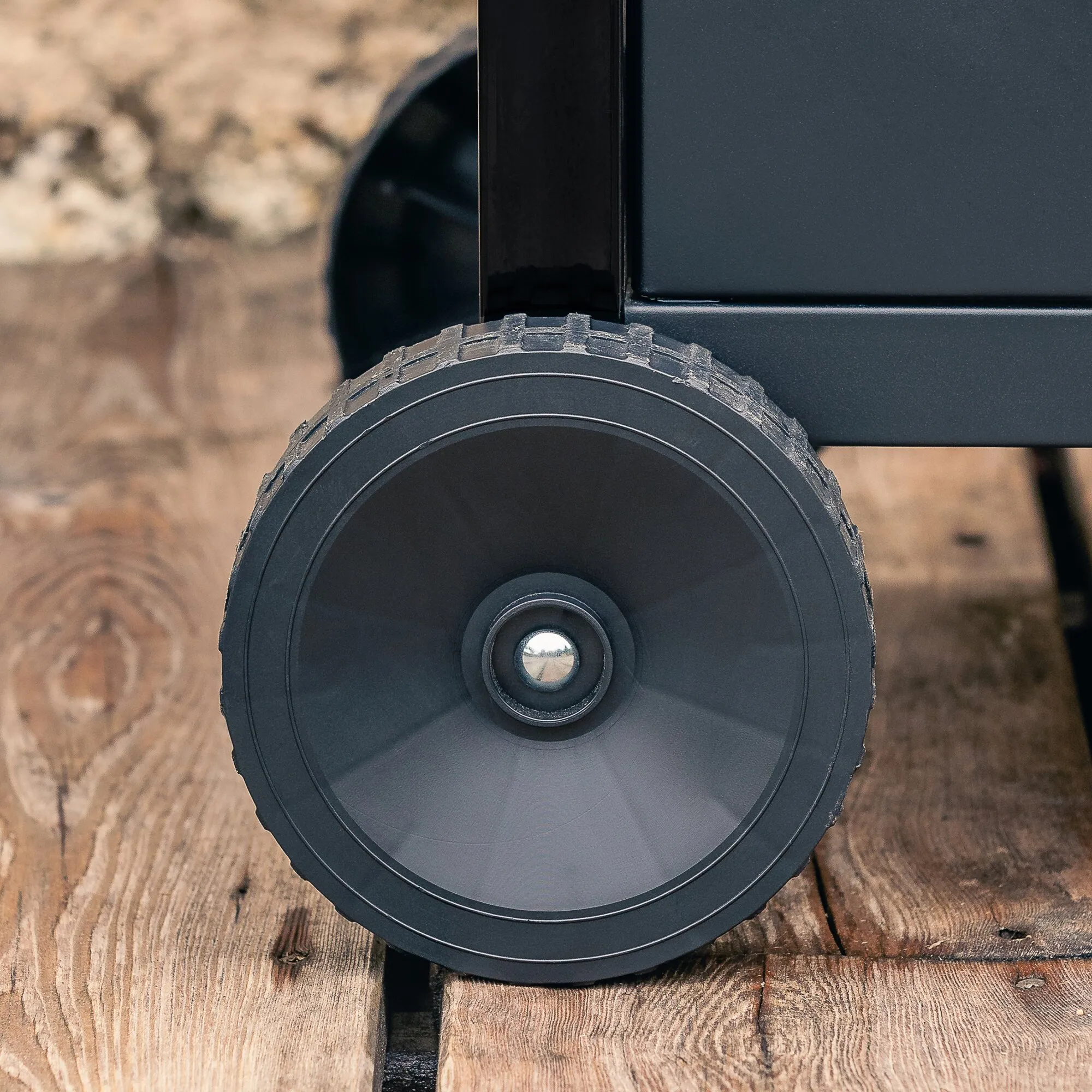Detailaufnahme des schwarzen Rads und Gehäuses des Gasgrills Compact 3 L auf einer Holzterrasse