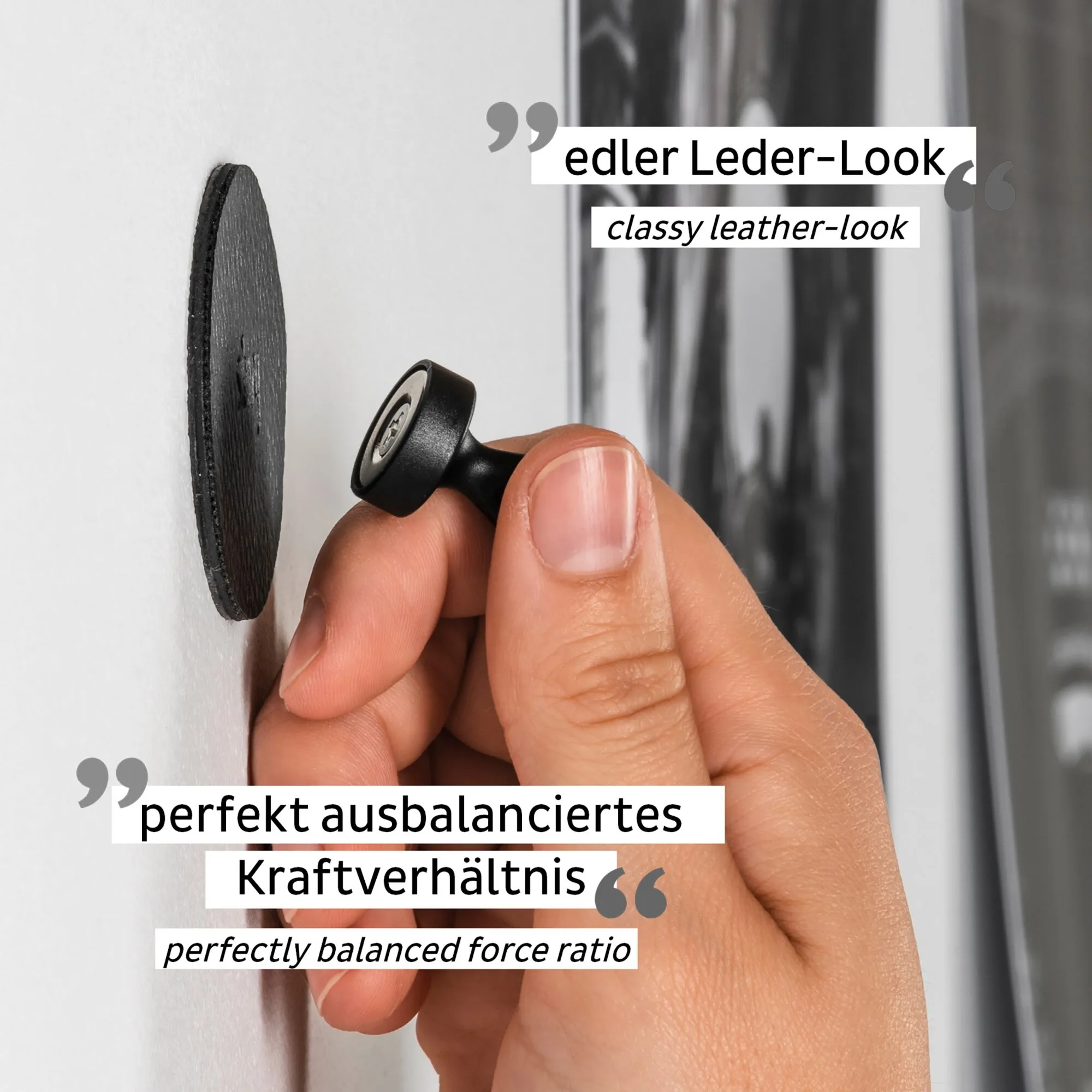 Schwarzer Magnet-Pin FLEX in Lederoptik wird von einer Hand an eine weiße Wand geführt, Detailaufnahme der Magnetbefestigung