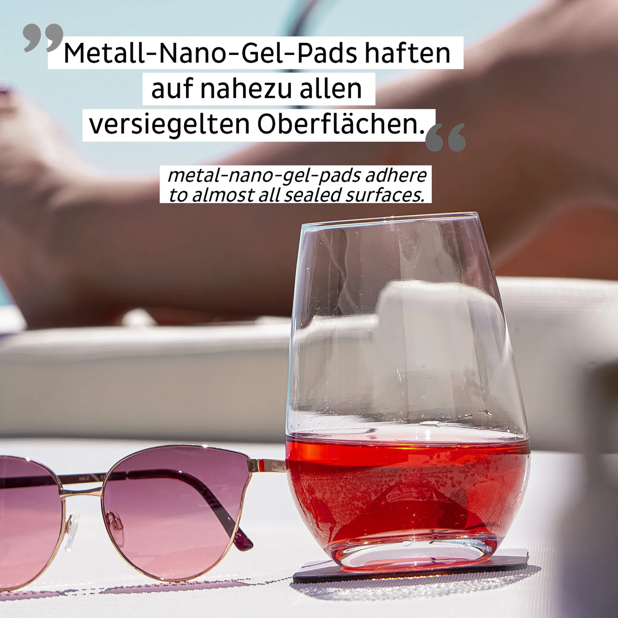 Klares Magnet-Kristallglas als Longdrinkglas mit rotem Getränk auf schwarzem Gel-Pad neben einer Sonnenbrille, Text zu Metall-Nano-Gel-Pads