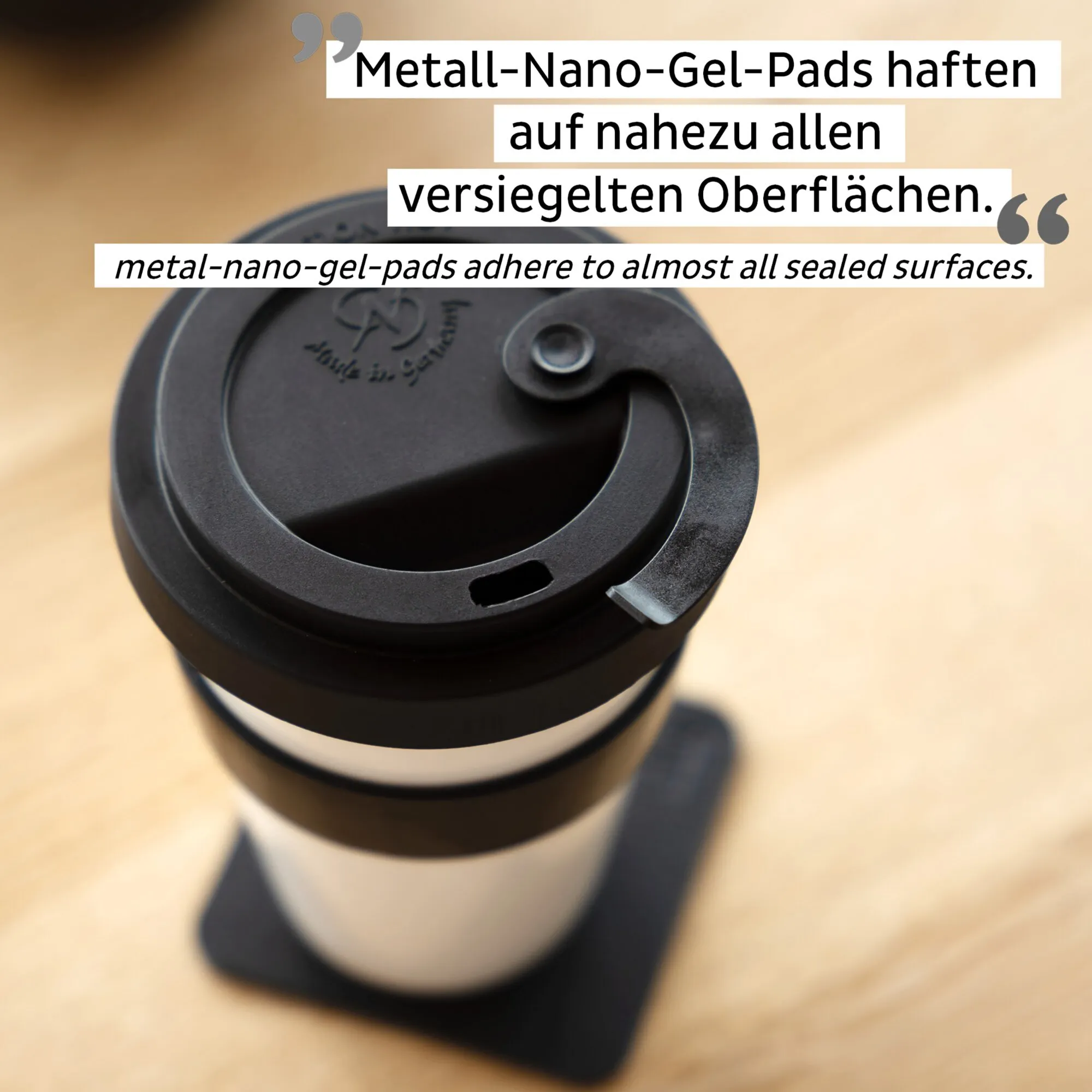 Porzellan-Kaffeebecher TO-GO-CUP mit schwarzem Deckel, Trinköffnung und Metall-Nano-Gel-Pads auf einem Holztisch