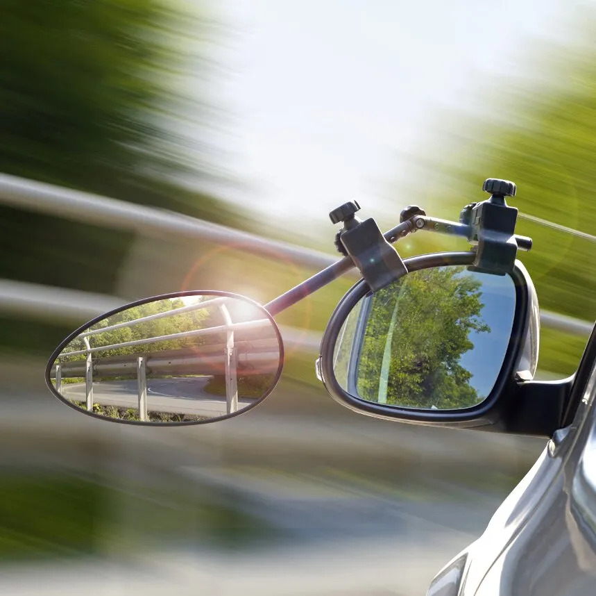 Schwarzer Caravanspiegel Speed Fix Mirror XXL am Außenspiegel eines fahrenden Autos, mit ovaler Zusatzspiegelfläche und Blick auf die Straße