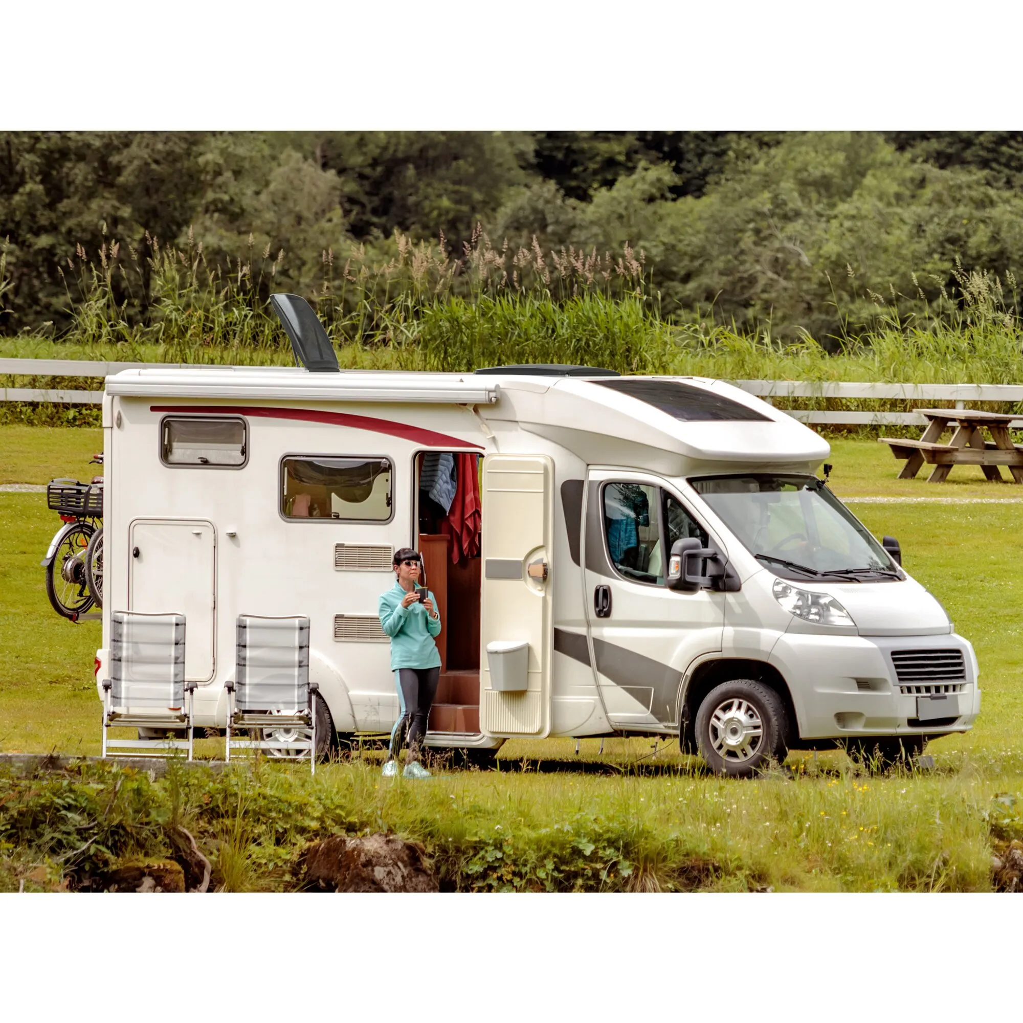 Seitenansicht eines weißen Wohnmobils auf einem Campingplatz mit geöffneter schwarzer Dachhaube roofSTAR 4 mit Zwangsbelüftung