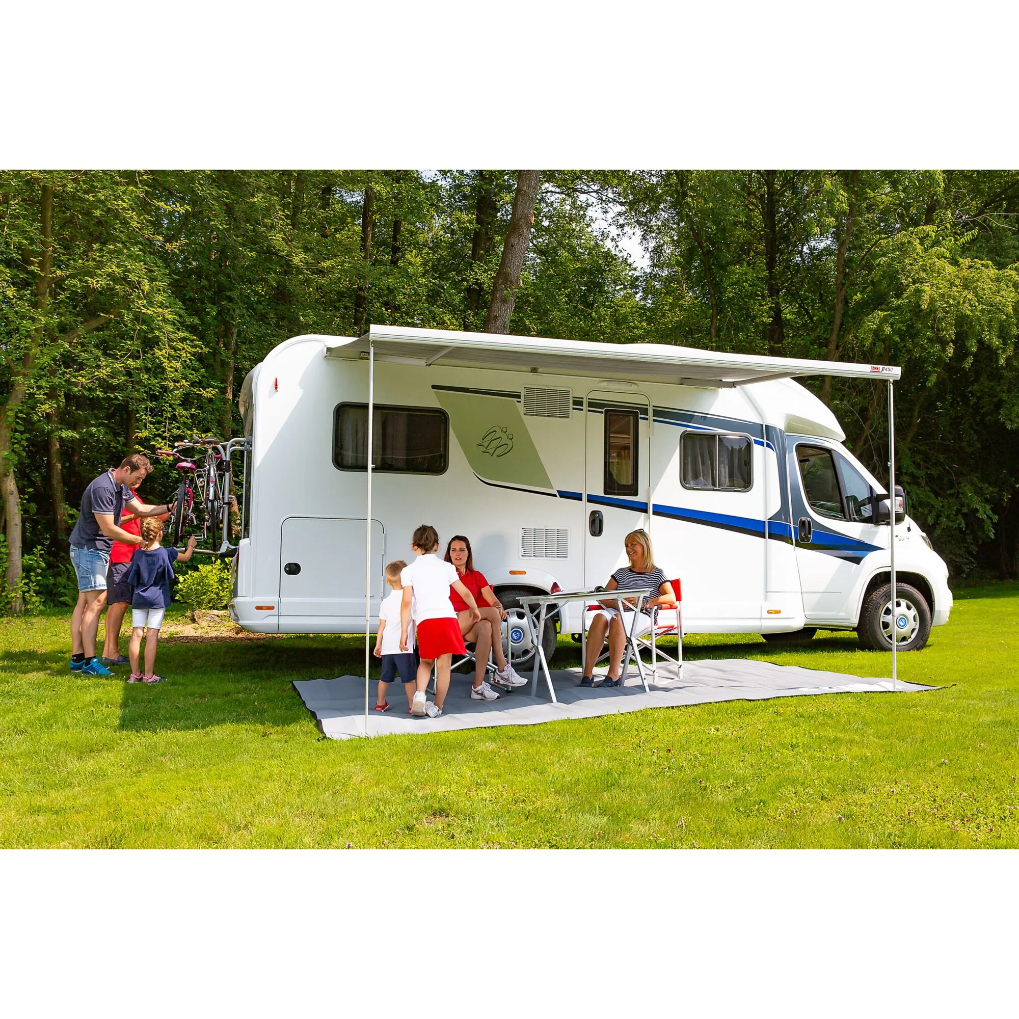 Polarweiße F45-Markise in Royal Blue, 348 cm, ausgefahren an einem Wohnmobil mit Familie auf einer Wiese im Wald