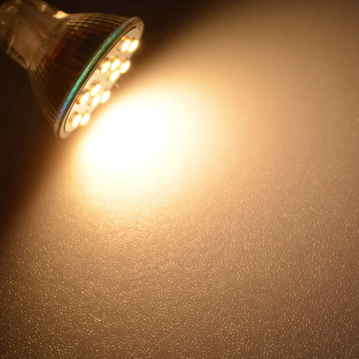 LED-Leuchtmittel GU4 mit 2 Watt und mehreren warmweiß leuchtenden LEDs in einem Reflektor an einer Wand
