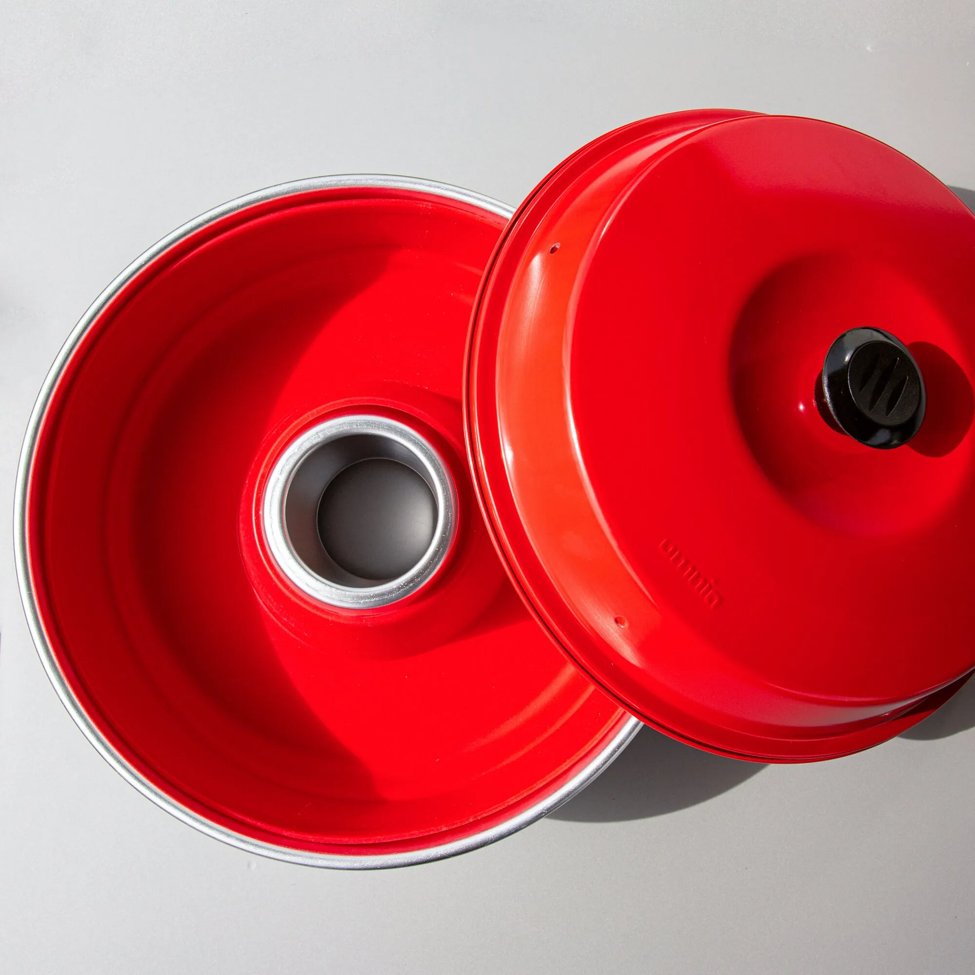 Rote runde Silikonform mit zentralem Einsatz und abnehmbarem Deckel mit schwarzem Verschluss, Innenansicht eines Stücks