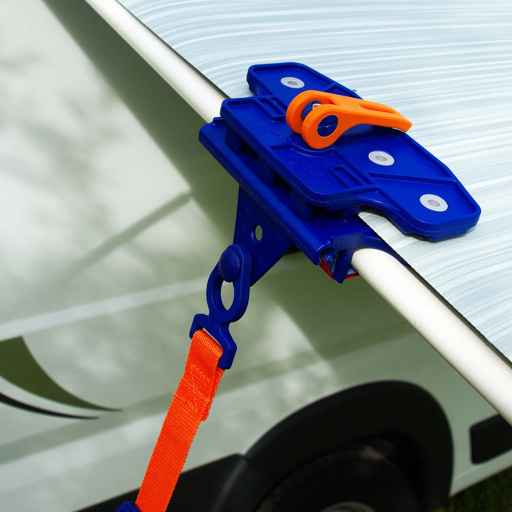 Blaue PP-Markisenklemme Fix&Go AntiFlap mit orangefarbenem Hebel an einer Markisenstange, befestigt mit orangefarbenem Gurt