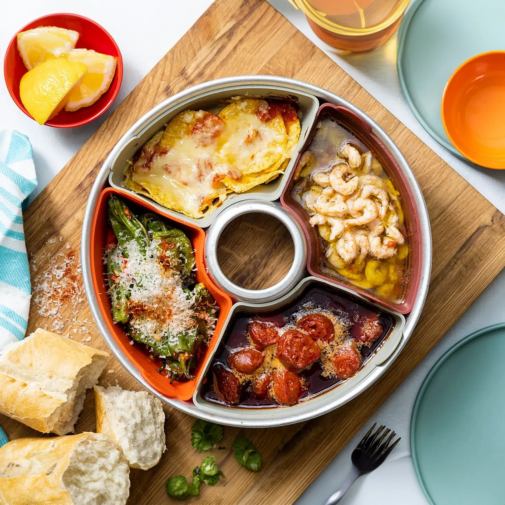 Set mit 6 farbigen Silikonformen in runder Backform, gefüllt mit überbackener Pasta, Garnelen, Gemüse und Tomaten gras.