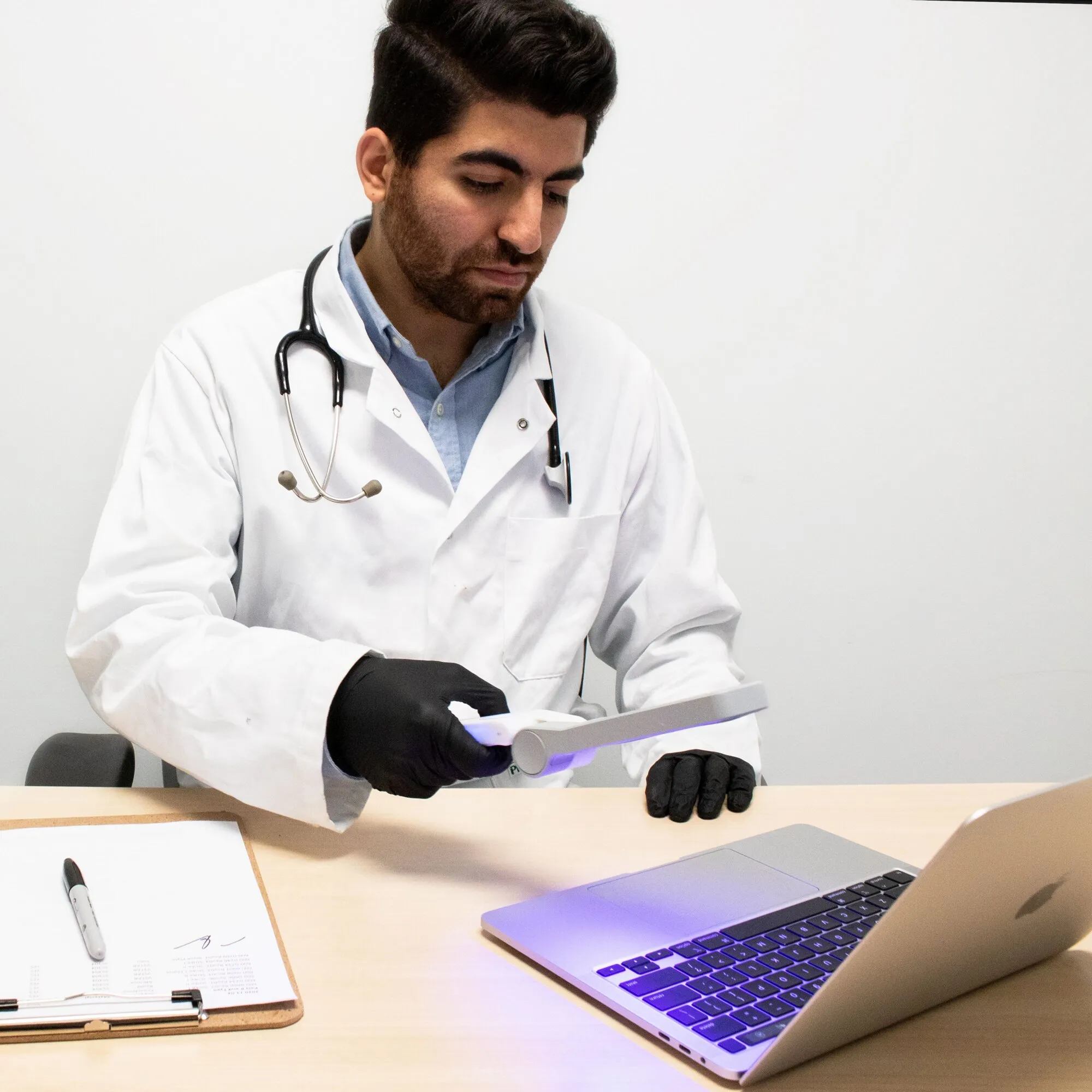 Arzt in Laborkittel und Handschuhen führt ein violett-weißes Acuva™ Solarix Gerät zur Oberflächendesinfektion über einen Tisch