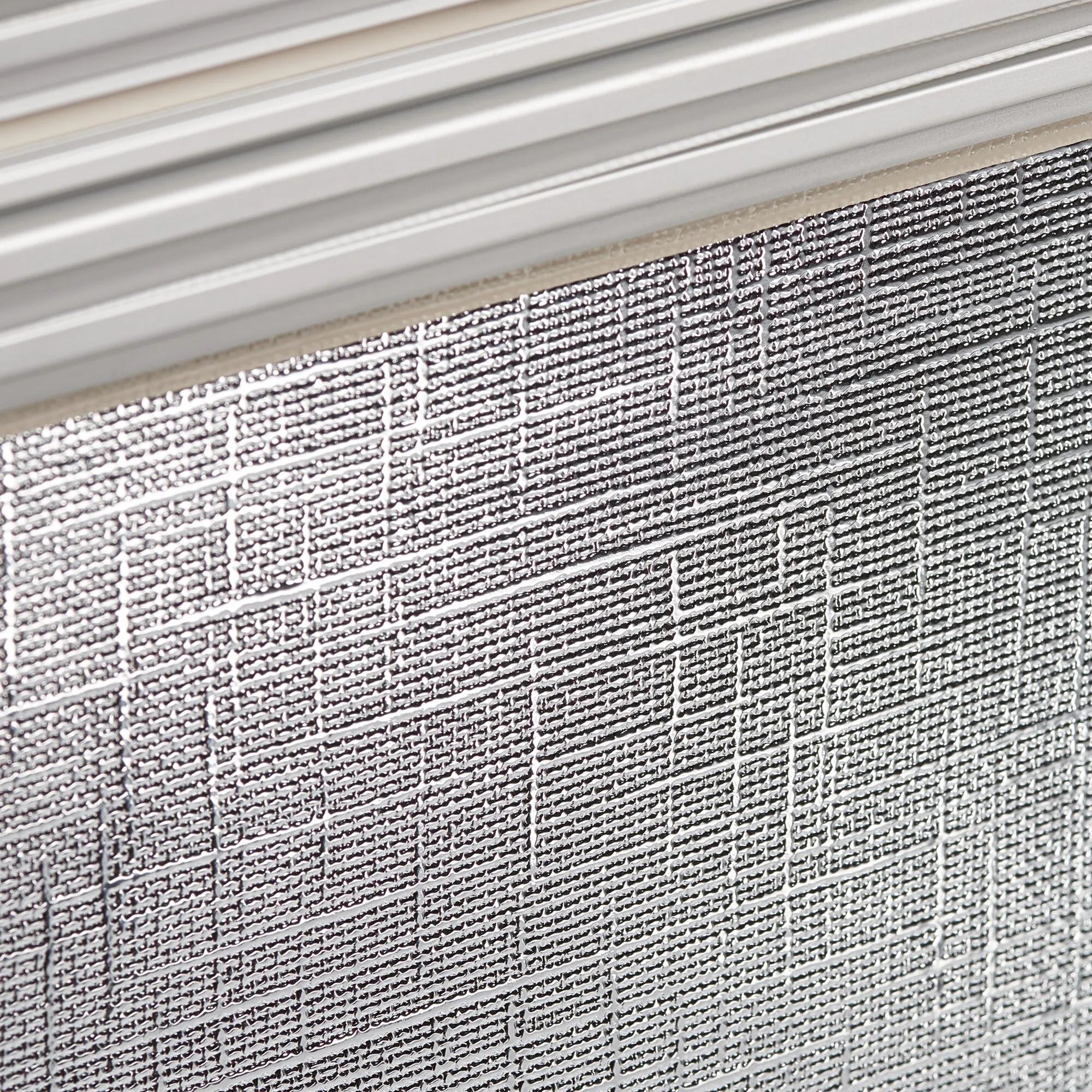 Detailaufnahme des silberfarbenen, strukturierten Gewebes und der weißen Führungsschiene des Dometic DB1R Rollosystems 1280 x 630 mm