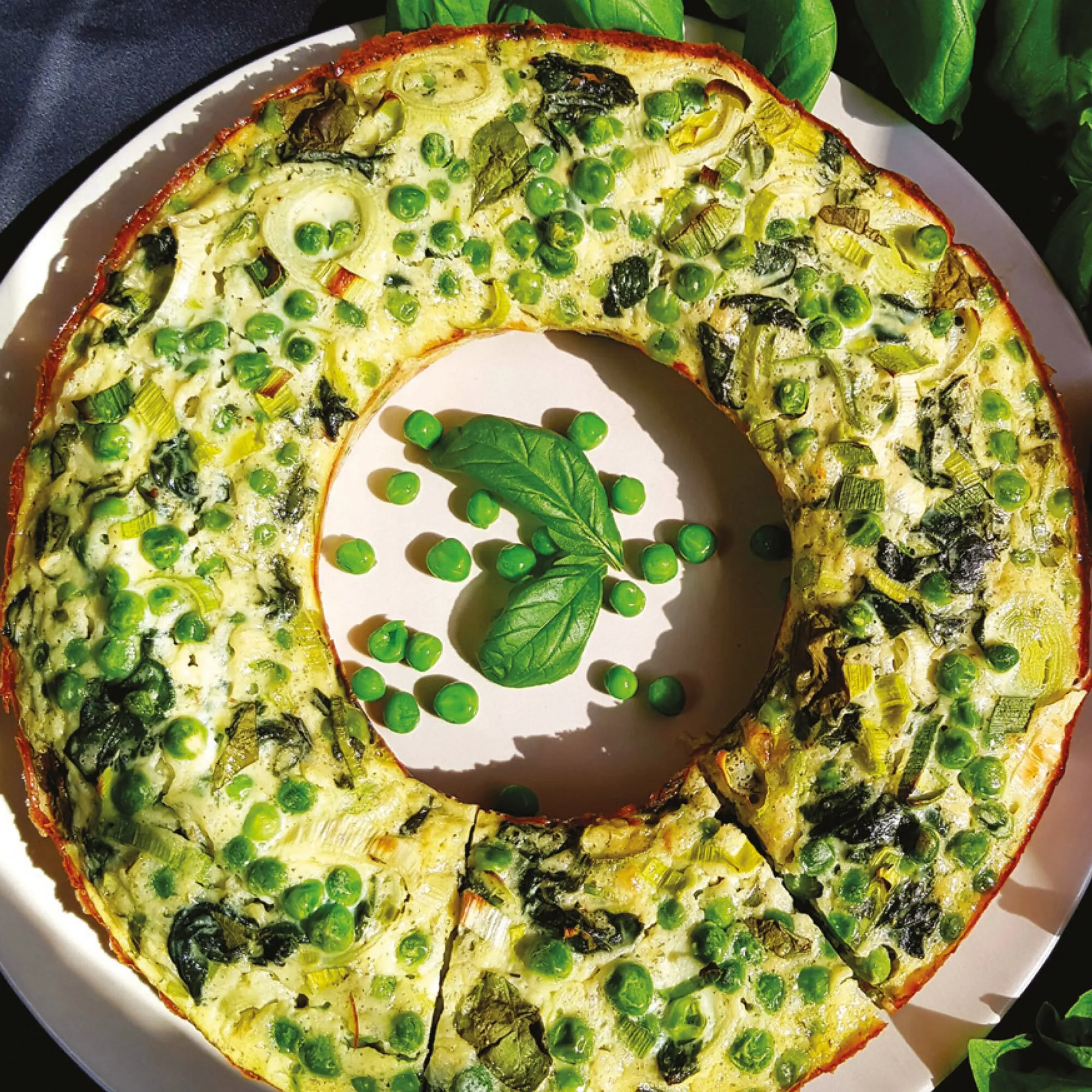 Grüner Gemüsekranz mit Erbsen, Lauch und Blattspinat auf einem weißen Teller – Rezept aus dem Omnia-Backofen-Kochbuch