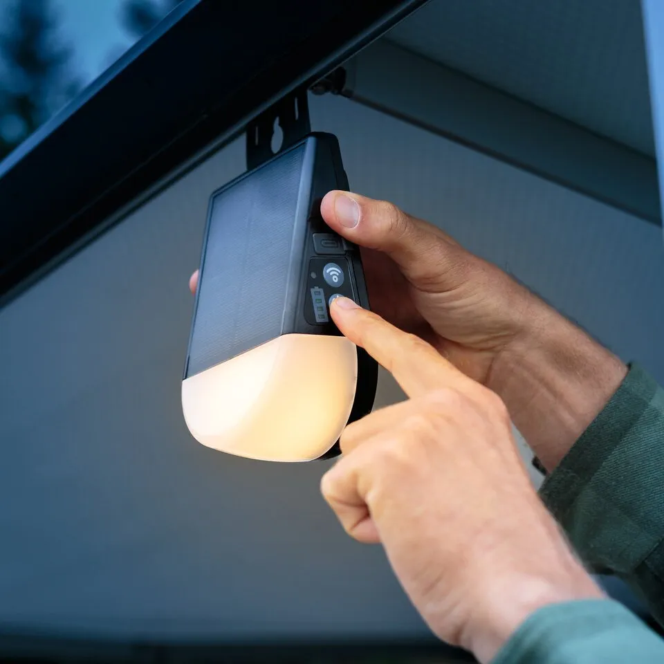Akku-Outdoor-Solarlampe KL 300 AS mit Bewegungsmelder, von einer Hand unter einem Dachvorsprung bedient