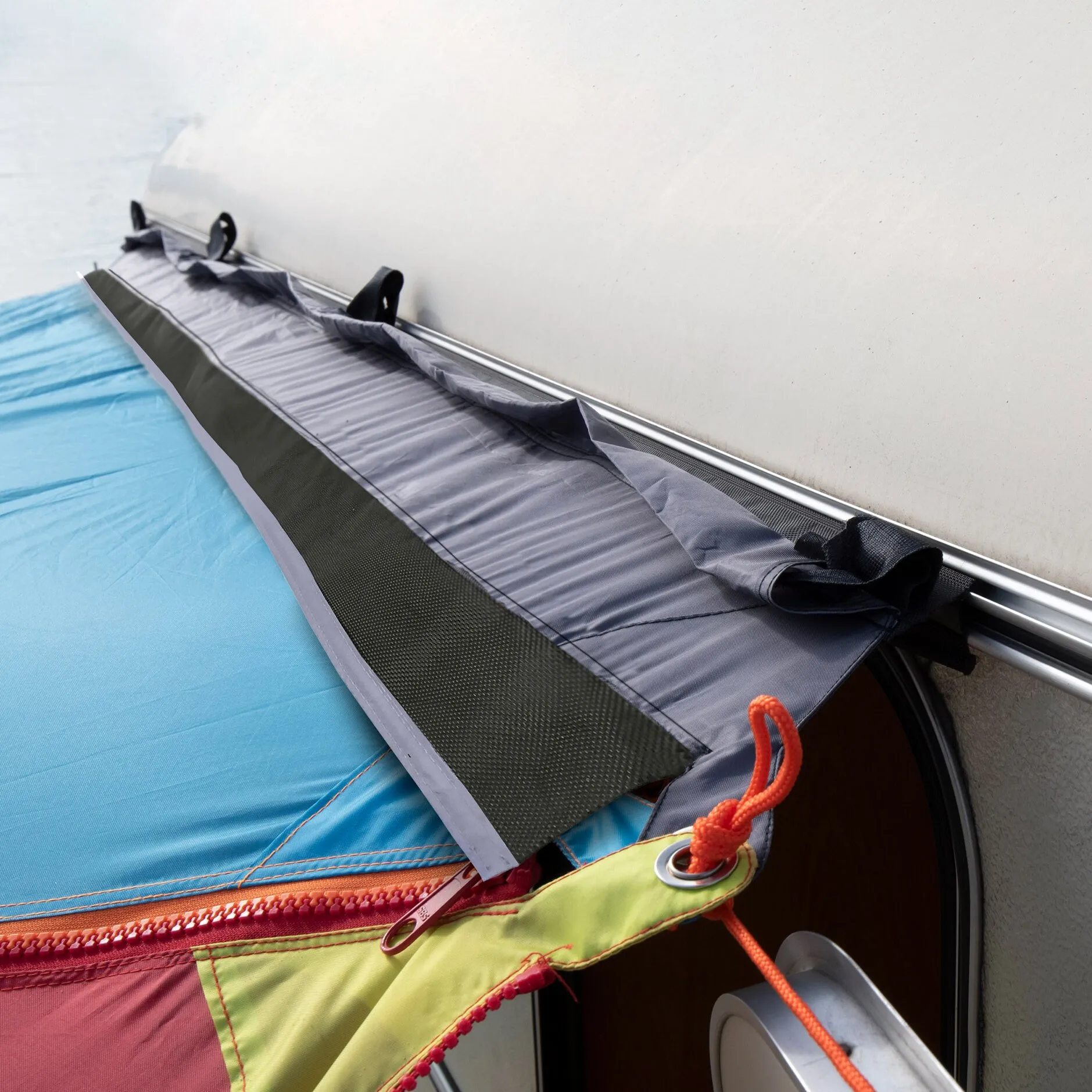 Grauer Universal-Fahrzeugadapter mit Befestigungsschlaufen an einer textilen Plane auf dem Dach eines Fahrzeugs