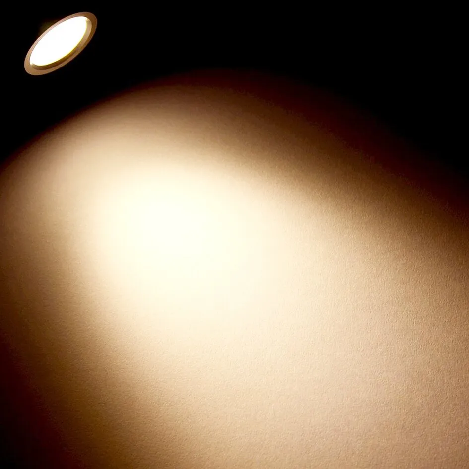 Ovale LED-Aufbauleuchte Schwanenhals in dunkler Ausführung beleuchtet eine strukturierte Wand mit warmweißem Licht