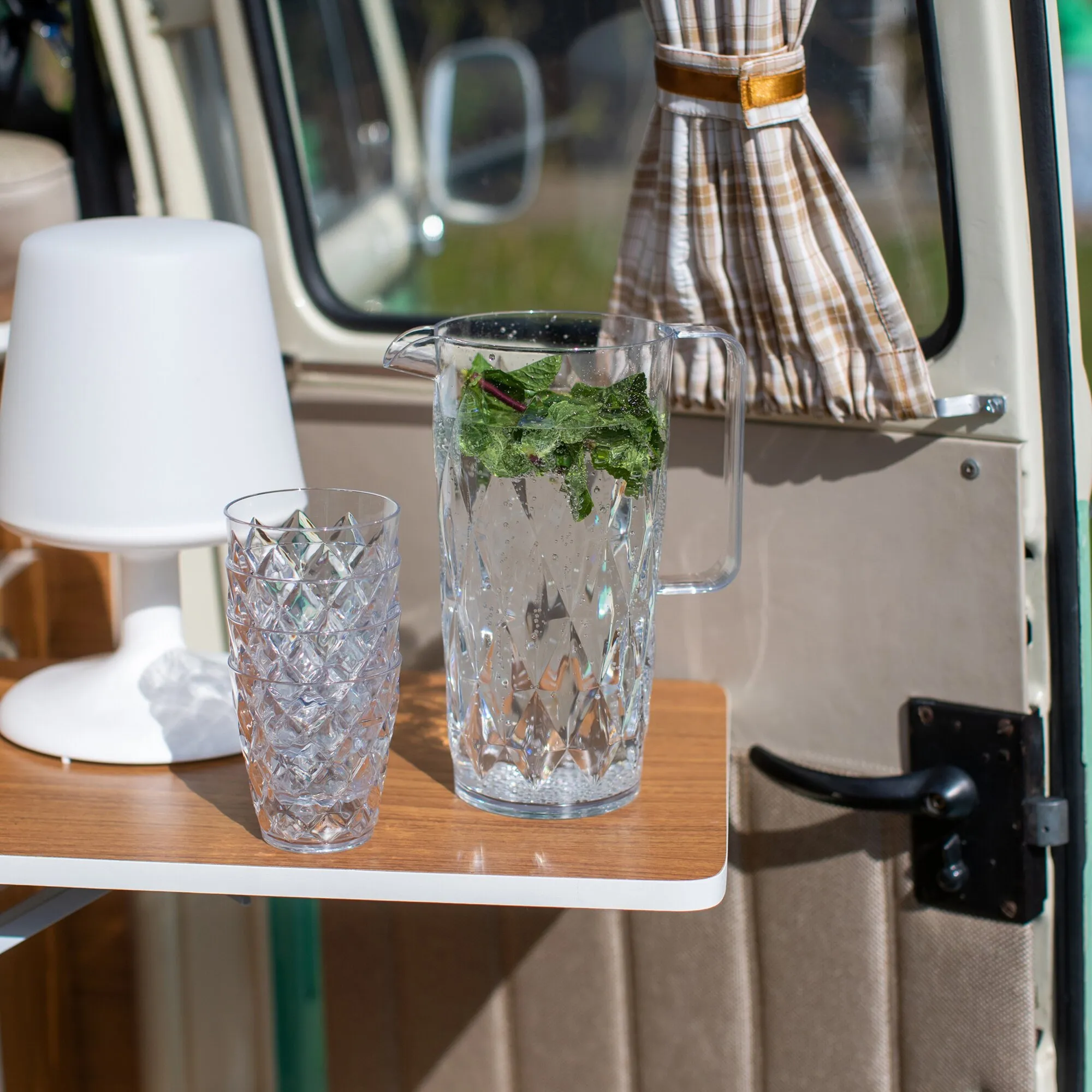 Transparente CRYSTAL-Glaskanne mit geometrischem Muster, Minze und vier passenden strukturierten Bechern auf einem Holztisch