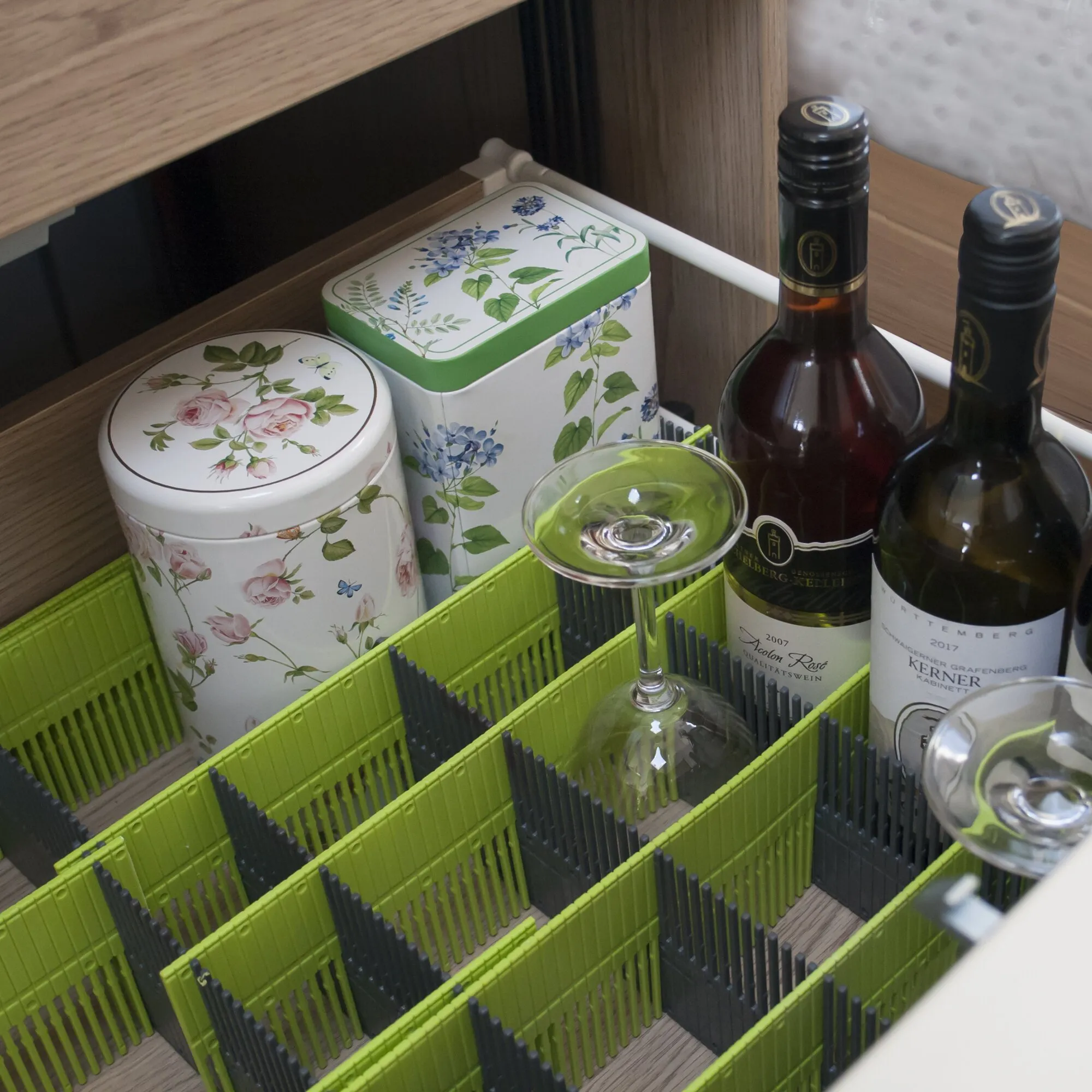 Limegrüne Stauleiste 100 MAXXI bildet in einem Küchenschrank Fächer für Weinflaschen, Dosen und Gläser