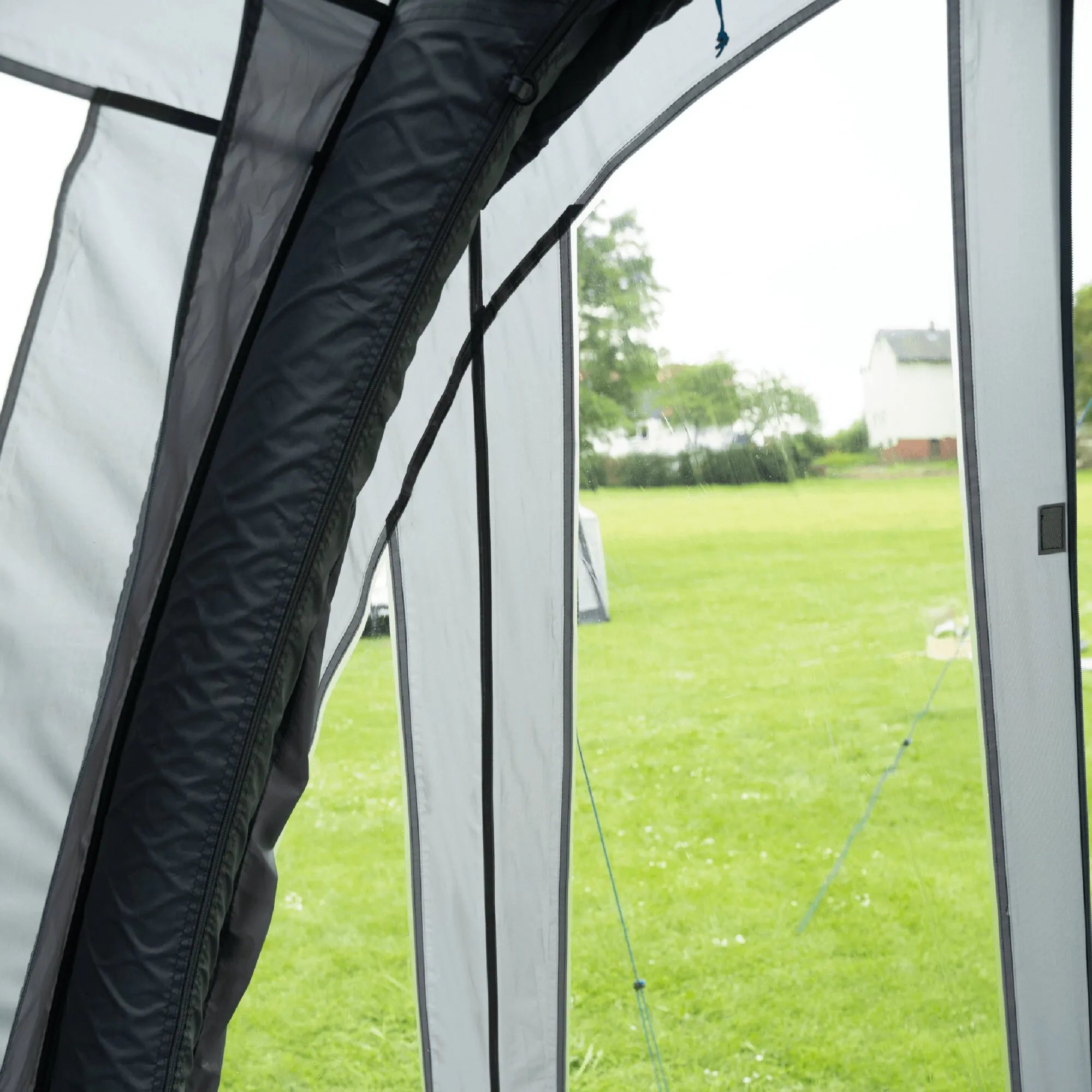 Innenansicht des Teilzelts Hydra mit transparenten Fensterflächen, schwarzen Reißverschlüssen und Blick auf eine grüne Wiese