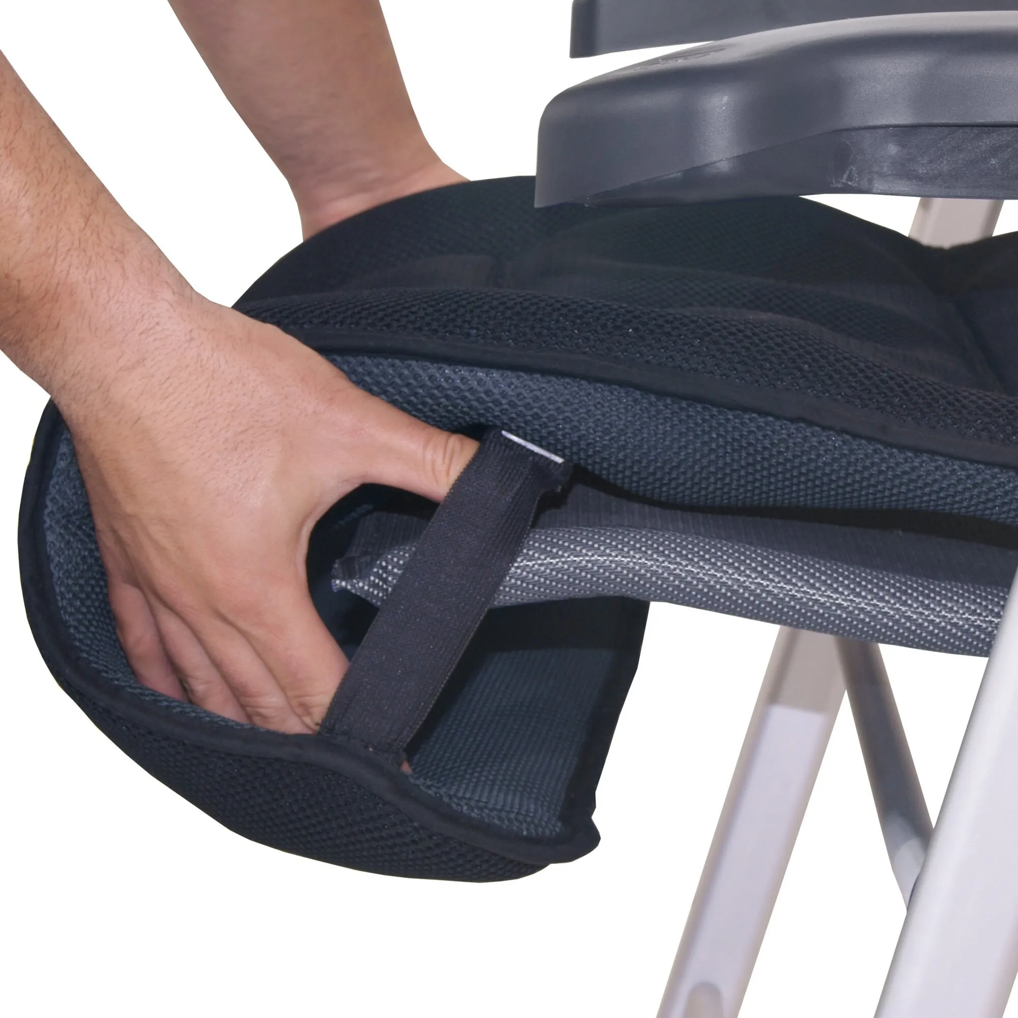 Detailaufnahme der schwarzen Polsterauflage Air-Deluxe, während eine Hand sie an einem Sitz befestigt
