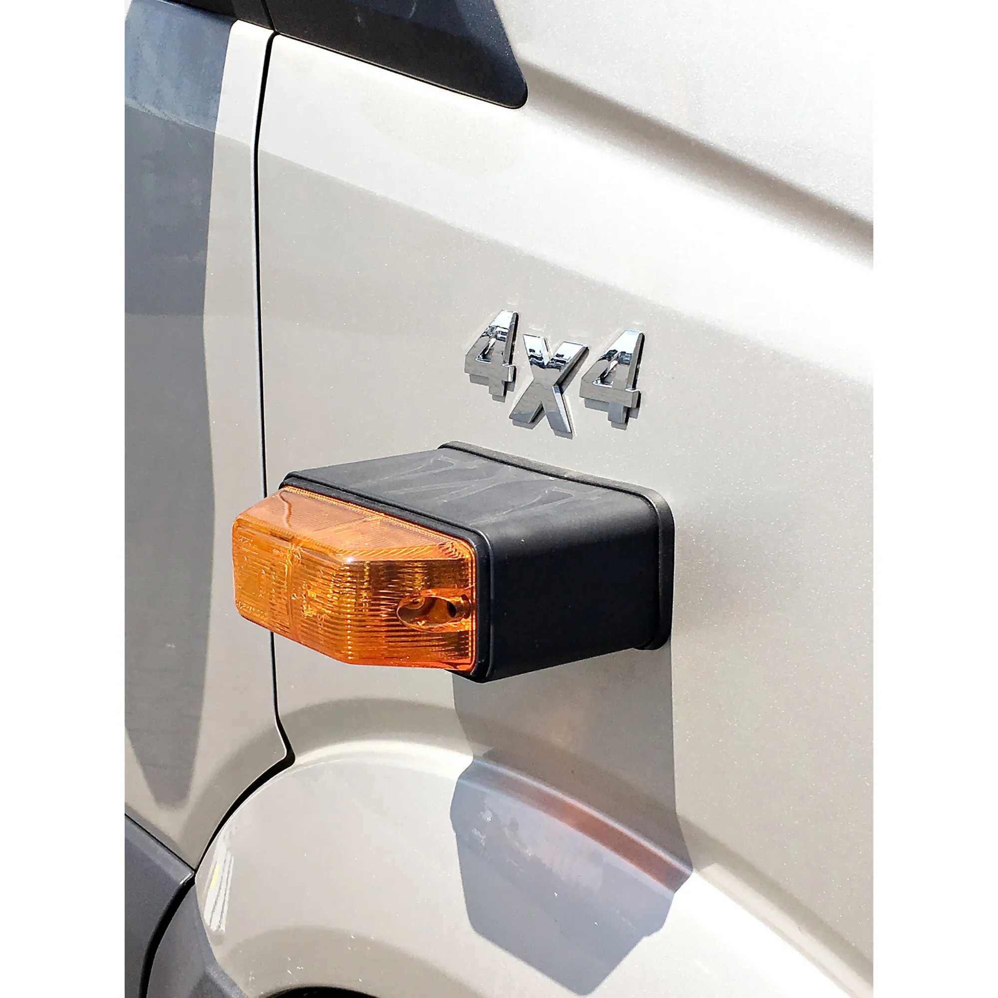 Detailaufnahme der weißen Fahrzeugkarosserie mit 4x4-Emblem und orangefarbenem seitlichem Blinker
