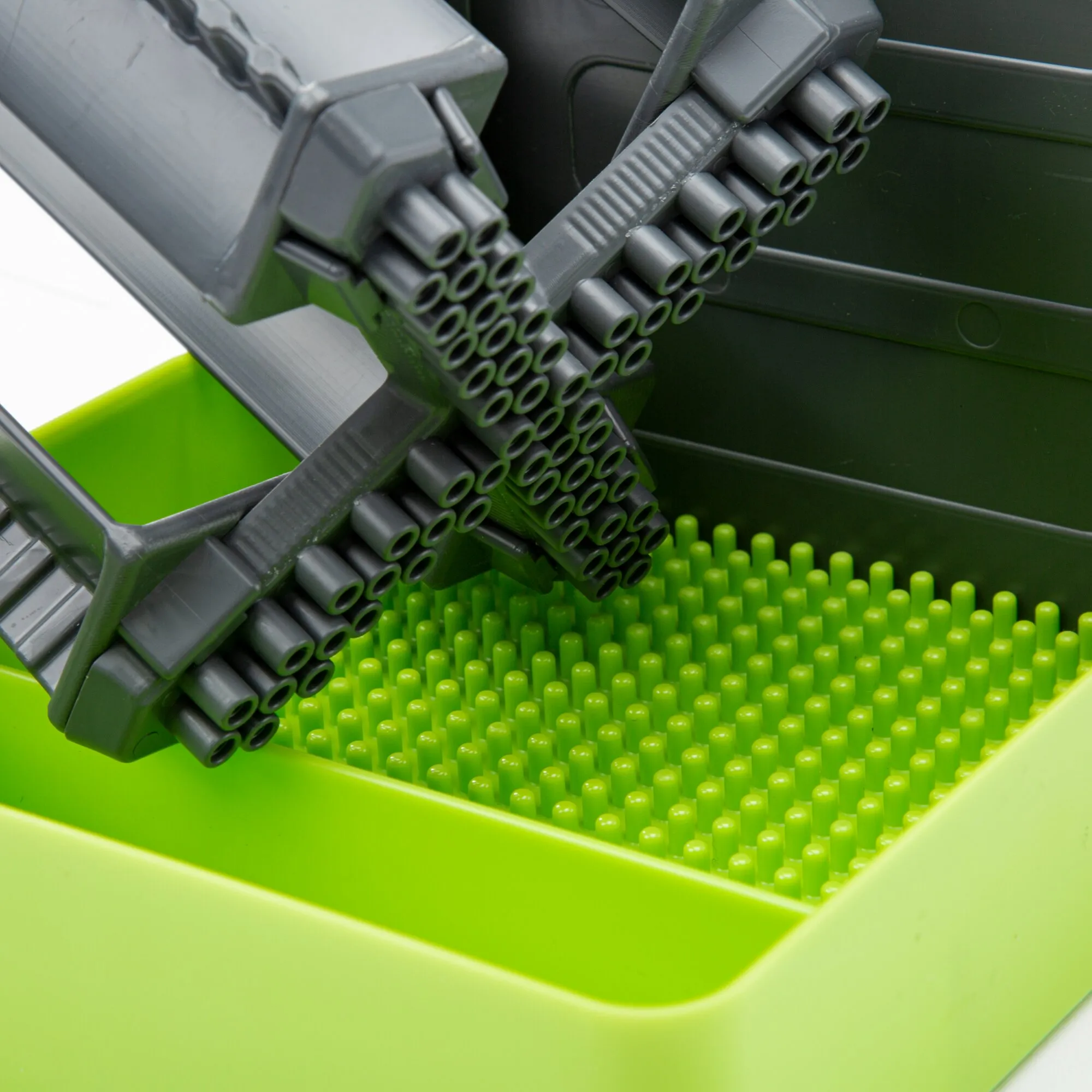 Detailaufnahme des grauen Flaschenhalters Multi Tray OELE in einer limefarbenen Ablage mit Noppenboden